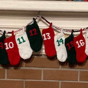 May include: A Christmas advent calendar made of knitted stockings with numbers 1 through 24, hung on a white fireplace mantel.