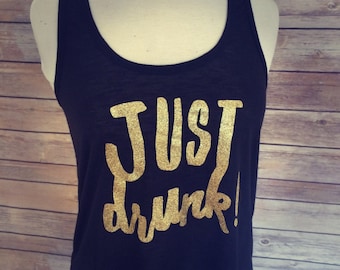 May include: Black tank top with gold glitter lettering that reads "JUST drunk!"