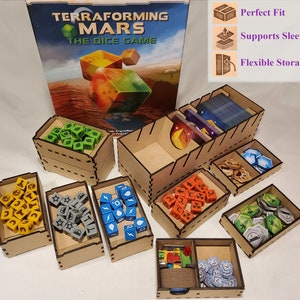 May include: Terraforming Mars The Dice Game organizer with multiple compartments for storing game components, including dice, cards, and tokens. The organizer is made of wood and has a natural finish. The game box is also shown in the image.