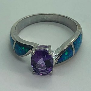 May include: A silver ring with a purple amethyst gemstone and blue opal accents.