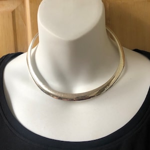 May include: A silver chain necklace with a textured finish. The necklace is a choker style and is worn on a mannequin.