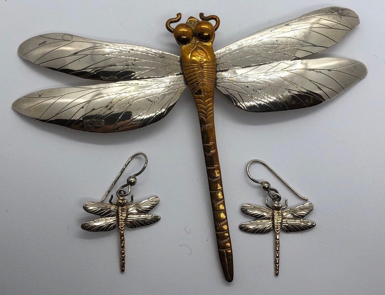 Puede incluir: Broche de lib&eacute;lula de plata con cuerpo dorado y pendientes a juego. La lib&eacute;lula tiene alas detalladas y un cuerpo texturizado.