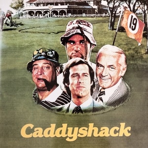 May include: Movie poster for the comedy film Caddyshack, featuring Chevy Chase, Rodney Dangerfield, Ted Knight, Michael O'Keefe, and Bill Murray. The poster has a yellow and gold title with a green golf course background.