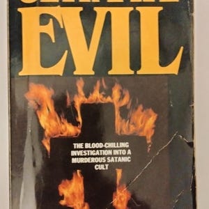 May include: A book cover with a yellow title "THE ULTIMATE EVIL" and a fiery cross image. The text below the image reads "THE BLOOD-CHILLING INVESTIGATION INTO A MURDEROUS SATANIC CULT". The author's name is "MAURY TERRY".