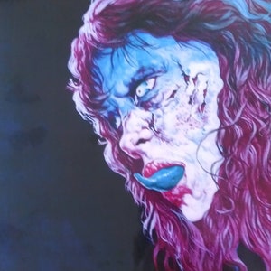 May include: A close-up of a woman's face with blue and white makeup. Her hair is long and pink. She is sticking her tongue out, which is painted blue.