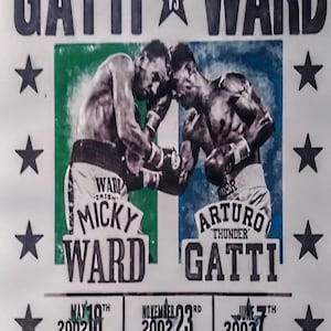 May include: A black and white poster advertising a boxing match between Micky Ward and Arturo Gatti. The poster features a photo of the two boxers in action, with the text "The Trilogy" and "Gatti vs Ward" at the top. The poster also includes the dates of the three fights in the trilogy: May 18th, 2002, November 23rd, 2002, and June 7th, 2003.