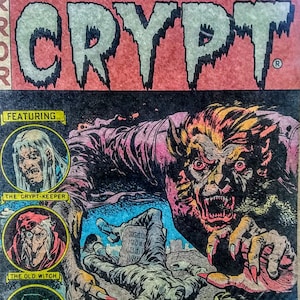 May include: A vintage comic book cover featuring a werewolf attacking a man in a graveyard. The cover is red, yellow, and blue with the title "Tales From The Crypt" and the issue number "No. 2".