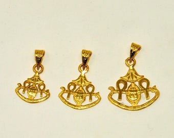 May include: Three gold-colored pendants with an Egyptian theme. Each pendant features a stylized design with an ankh symbol and other Egyptian motifs. The pendants vary in size, with the smallest on the left and the largest on the right.
