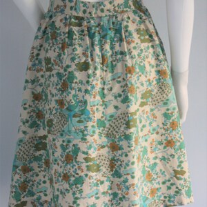 May include: A white skirt with a floral print featuring peacocks and flowers in shades of blue, green, and orange.