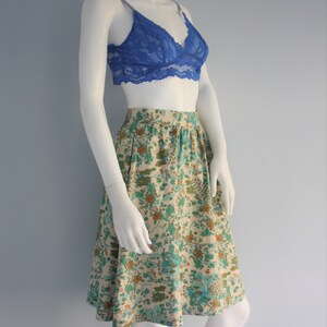 May include: A white floral print skirt with a blue lace bralette. The skirt has a high waist and a flared silhouette.