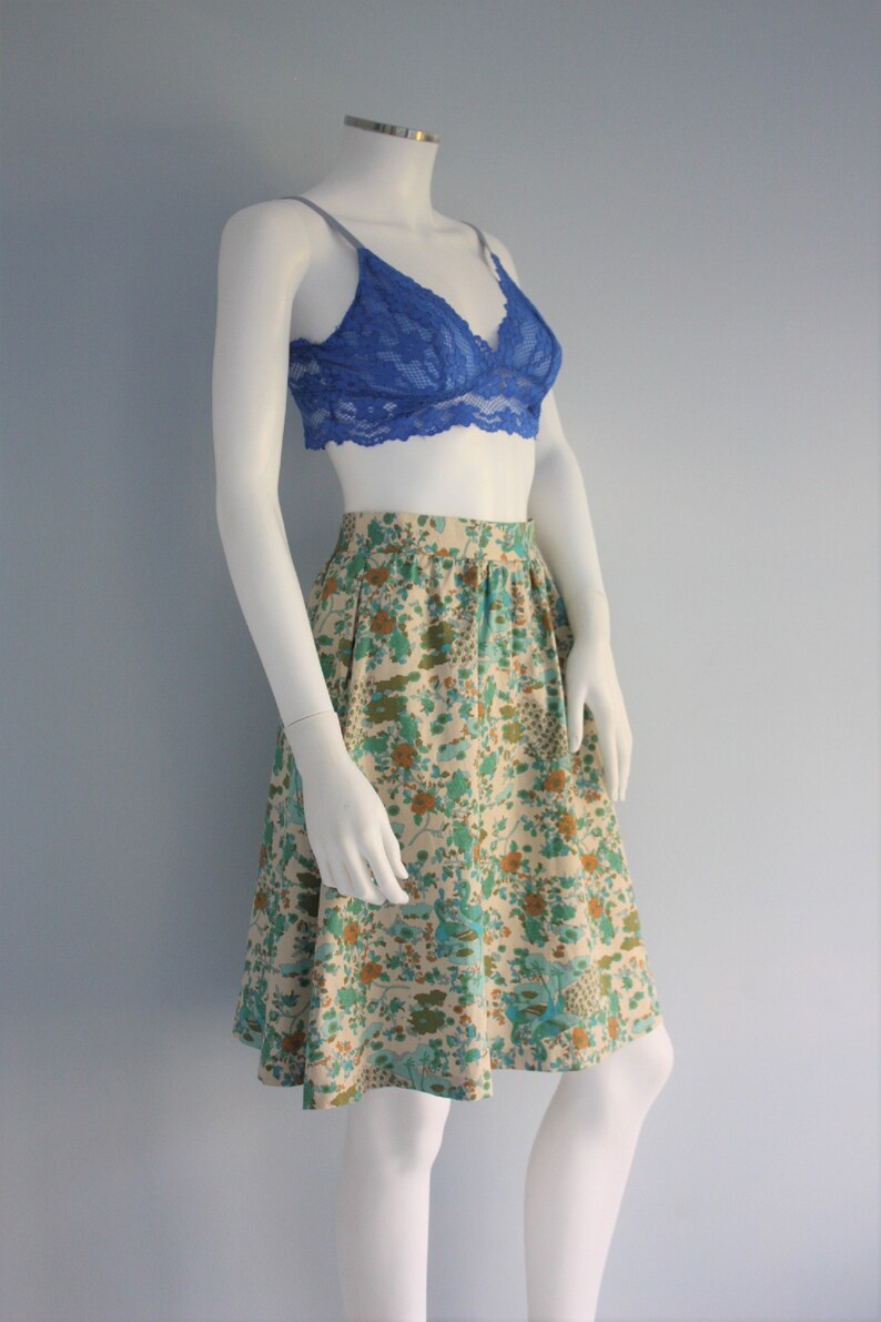 May include: A white floral print skirt with a blue lace bralette. The skirt has a high waist and a flared silhouette.