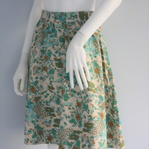 May include: A white, floral print skirt with a blue, green, and brown pattern. The skirt is knee-length and has a gathered waist.