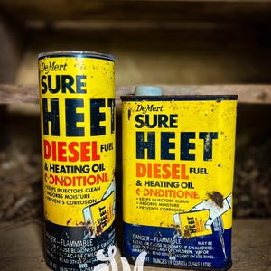 May include: Two yellow cans of DeMert Sure Heet Diesel Fuel & Heating Oil Conditioner. The cans have black text and a red and blue logo. The text on the cans reads "DeMert Sure Heet Diesel Fuel & Heating Oil Conditioner" and "Keeps injectors clean, absorbs moisture, prevents corrosion".