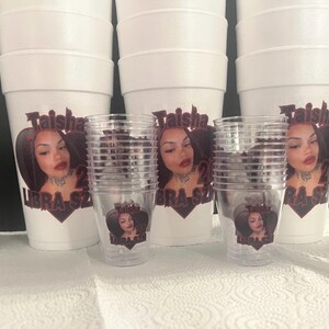 Puede incluir: Vasos de espuma blancos y vasos de pl&aacute;stico transparente con un dise&ntilde;o impreso. El dise&ntilde;o presenta la cara de una mujer, el nombre "Taisha", el n&uacute;mero "28" y las palabras "Libra Szn" en un gr&aacute;fico en forma de coraz&oacute;n.