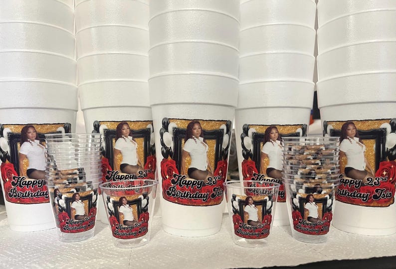 Puede incluir: Una colecci&oacute;n de vasos de espuma blancos y vasos de chupito de pl&aacute;stico transparente. Cada vaso y vaso tiene una foto de una mujer, enmarcada con un borde dorado, rosas rojas y el texto "Happy 23rd Birthday Tsis."