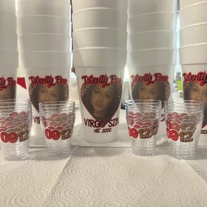 Puede incluir: Vasos de espuma blancos y vasos de chupito transparentes con dise&ntilde;os personalizados. Los vasos presentan un dise&ntilde;o en forma de coraz&oacute;n con una foto, el texto "Twenty Fine" y "Virgo SZN est. 2000". Los vasos de chupito tienen un dise&ntilde;o rojo y marr&oacute;n con el texto "0912".