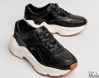 May include: A pair of black leather sneakers with white soles and a chunky platform. The sneakers have a textured design and a lace-up closure.