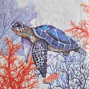 May include: A decorative paper napkin featuring a sea turtle swimming among coral and seaweed. The turtle has a blue and black shell, with a patterned design. The coral is red and the seaweed is purple and blue.