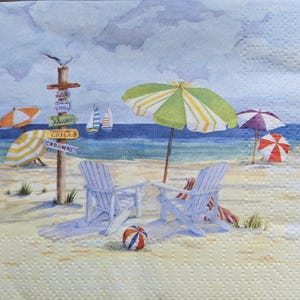 May include: A square paper napkin featuring a watercolor beach scene with two white Adirondack chairs, a green and white striped umbrella, and a small ball on the sand. A wooden signpost displays text including Grill and Cabanas near the ocean.