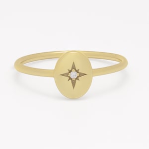 Op de afbeelding: Een gouden ring met een kleine diamant in een ovaalvormig ontwerp met een stervormig patroon.