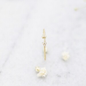 May include: A delicate gold ring with two clusters of small diamonds. The ring is simple and elegant, perfect for everyday wear.