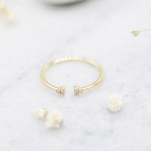 May include: A gold ring with a delicate open design and small diamonds on each side.