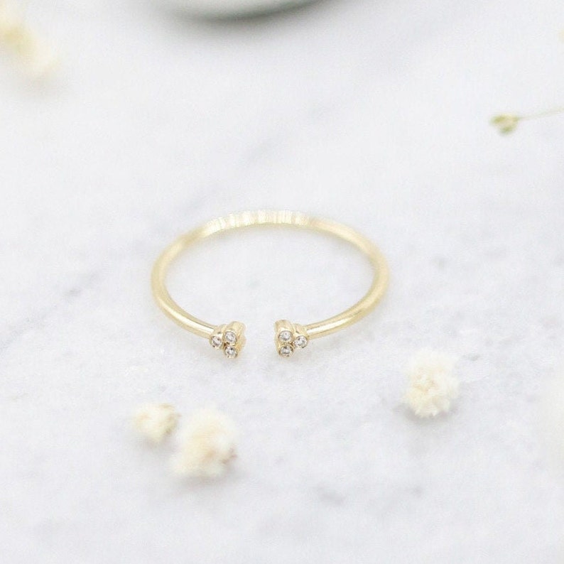 May include: A gold ring with a delicate open design and small diamonds on each side.