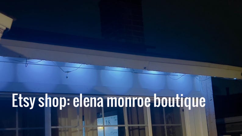K&ouml;nnte beinhalten: Au&szlig;enaufnahme bei Nacht mit blauen LED-Leuchten, die eine wei&szlig;e Markise beleuchten. Der Text "Etsy shop: elena monroe boutique" wird in wei&szlig;en Buchstaben am unteren Bildrand angezeigt.