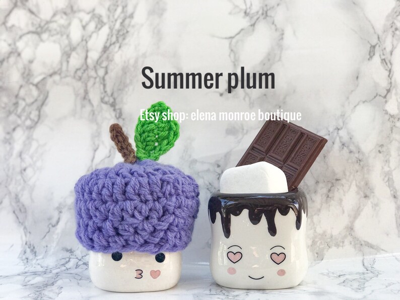 May include: Two ceramic mugs shaped like marshmallows with faces. One mug has a purple crocheted hat shaped like a plum with a green leaf. The other mug has a chocolate bar and a white marshmallow on top. The text "Summer plum" and "Etsy shop: elena monroe boutique" is on the background.