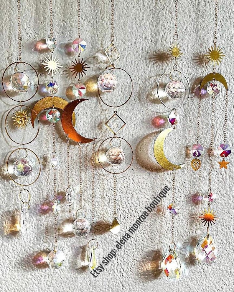 Peut inclure: Ornements d&eacute;coratifs suspendus avec des th&egrave;mes c&eacute;lestes. La conception comprend des soleils, des lunes et des formes g&eacute;om&eacute;triques dor&eacute;s, ainsi que des sph&egrave;res de cristal transparentes et des cristaux facett&eacute;s. Les ornements sont suspendus par de fines cha&icirc;nes.