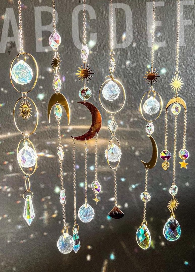 Peut inclure: Suncatchers d&eacute;coratifs en cristal suspendus avec des motifs c&eacute;lestes. Chaque capteur de soleil comprend une cha&icirc;ne dor&eacute;e, une boule de cristal transparente et divers breloques, dont des soleils, des lunes et des &eacute;toiles. Les cristaux r&eacute;fractent la lumi&egrave;re.