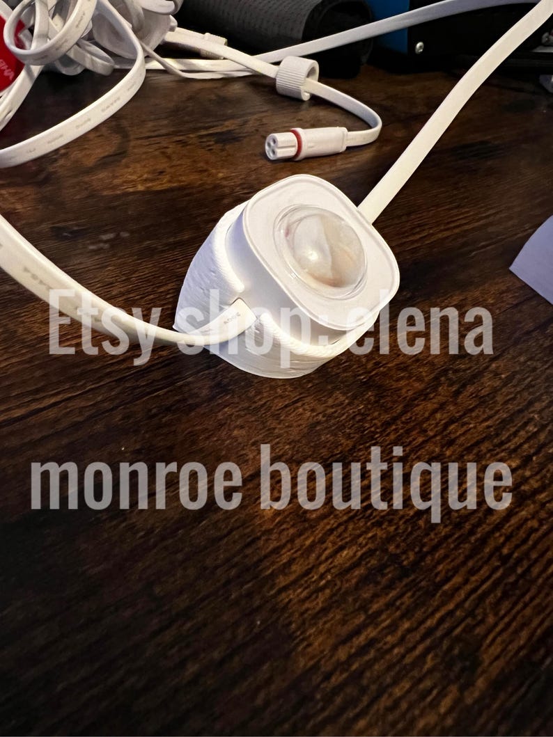 K&ouml;nnte beinhalten: Ein wei&szlig;es elektrisches Bauteil mit einer klaren, abgerundeten Linse, verbunden mit wei&szlig;en Kabeln. Der Text "Etsy shop lena" und "monroe boutique" sind sichtbar. Das Objekt liegt auf einer dunkelbraunen Holzoberfl&auml;che.