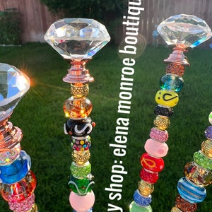 May include: Four colorful beaded garden stakes with crystal diamond tops. Each stake features a variety of colorful glass beads, including pink, blue, green, yellow, and red. The stakes are topped with clear crystal diamond-shaped finials.