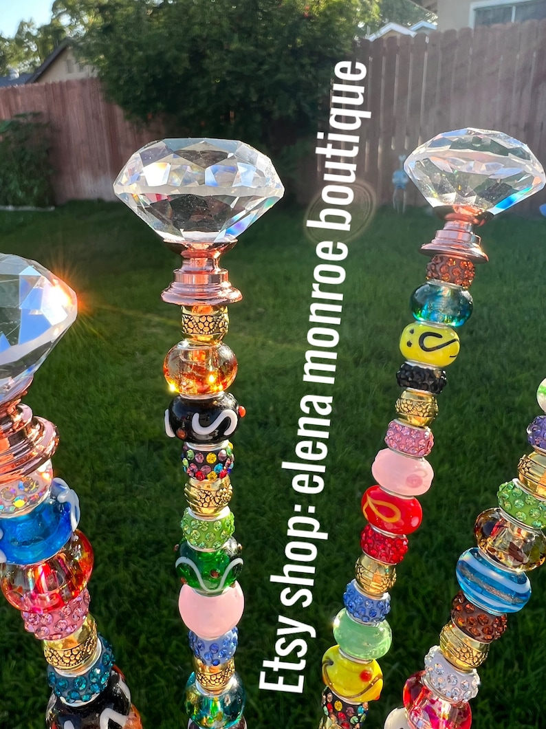 May include: Four colorful beaded garden stakes with crystal diamond tops. Each stake features a variety of colorful glass beads, including pink, blue, green, yellow, and red. The stakes are topped with clear crystal diamond-shaped finials.