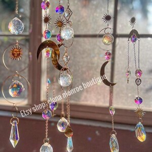 Peut inclure: Suns-catchers d&eacute;coratifs suspendus avec des prismes en cristal transparent, des cristaux iris&eacute;s et des soleils, lunes et &eacute;toiles en m&eacute;tal dor&eacute;. Les attrape-soleil sont suspendus par de fines cha&icirc;nes, cr&eacute;ant un affichage sur le th&egrave;me c&eacute;leste.