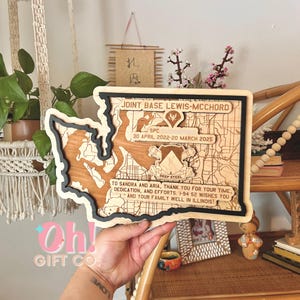 May include: Wooden map of Joint Base Lewis-McChord, with a black and natural wood border. The map includes text: "SPC 30 April 2022-20 March 2025" and "To Sandra and Aria, thank you for your time, dedication, and efforts."