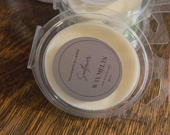 Op de afbeelding: Transparante plastic containers met wax melts in een crèmekleurige, gebroken witte kleur. Elke container heeft een rond etiket met het woord "Sunflower" in cursief en de woorden "Wax Melts". De tekst "Rejuvenate by Jenna" is ook zichtbaar.