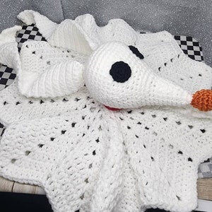 May include: White crocheted blanket with a white crocheted character resembling Jack Skellington from the Nightmare Before Christmas. The character has black eyes and an orange nose.