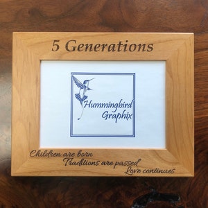 May include: A wooden picture frame with the text "5 Generations" engraved on the top. The frame has a white mat with the text "Hummingbird Graphix" and the text "Children are born, Traditions are passed, Love continues" engraved on the bottom.