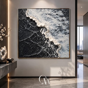 May include: A square wall art piece featuring a textured oil painting of a dark black ocean shoreline with thick, raised white paint creating the appearance of crashing waves and sea foam, framed in a thin, metallic gold border.