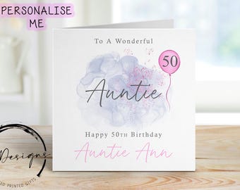 May include: A square white greeting card featuring the text To A Wonderful Auntie, Happy 50th Birthday, and Auntie Ann. The design includes a purple watercolour cloud, pink glitter accents, and a pink balloon with the number 50 printed on it.