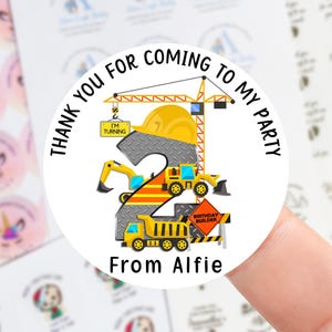 May include: Circular sticker with a construction theme for a second birthday. The design features a yellow crane, hard hat, and construction vehicles. Text reads "Thank you for coming to my party" and "From Alfie".