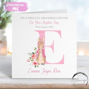 Pode incluir: Um cartão de batismo branco com a letra "E" rosa e uma ilustração em aquarela de um coelhinho com um casaco rosa. O cartão diz: "Para uma neta especial, No seu dia de batismo, 28 de agosto de 2024, Emma Jayne Rose."