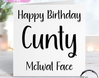 May include: White greeting card with the text "Happy Birthday C**ty McTwat Face" in black. The card has a pink banner that says "Personalise Me" in white. The card is on a wooden surface.