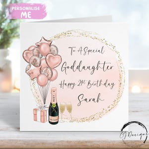 May include: A personalized birthday card with a pink and gold design. The card features a bouquet of pink balloons, a champagne bottle, two glasses, and a gift box. Text reads "To A Special Goddaughter, Happy 21st Birthday Sarah."