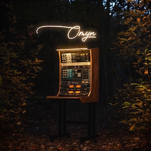 May include: A wooden audio rack with various electronic components, set against a backdrop of a forest. The word "Oryn" is written in a glowing script above the rack. The rack is supported by a black metal stand.