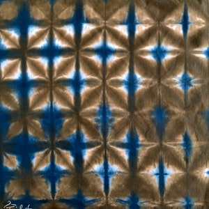 May include: A brown and blue tie-dye fabric with a geometric pattern. The fabric has a repeating pattern of stars and squares.