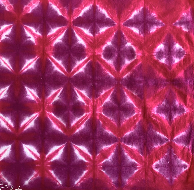 May include: A pink and white tie-dye fabric with a geometric pattern. The fabric has a repeating pattern of diamonds and stars.