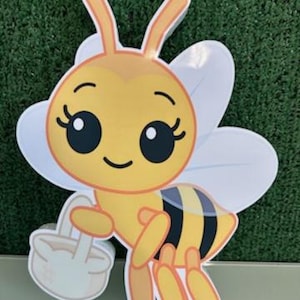 May include: A cartoon-style cutout of a bee, featuring a yellow body with black stripes and white wings. The bee has large, expressive eyes and is holding a small basket. The letter "A" is visible in the lower right corner.