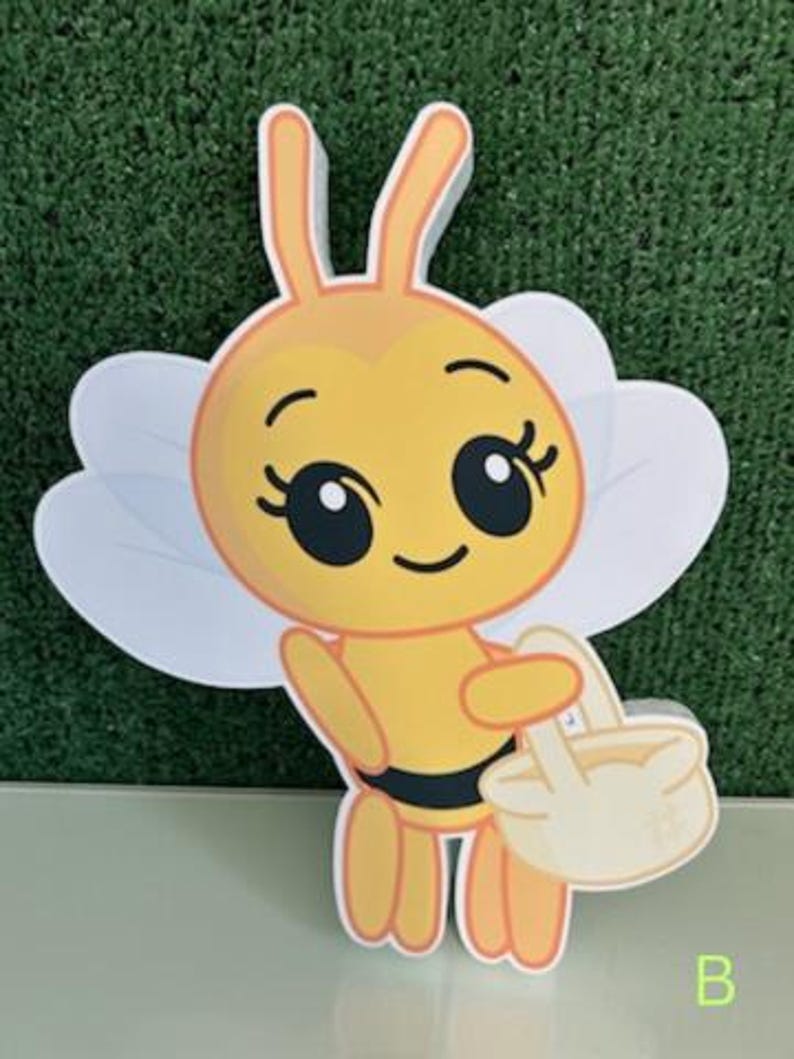 May include: A cartoon bee cutout with a yellow body, black stripes, and large eyes. The bee has white wings and is holding a light yellow basket. The letter "B" is in the bottom right corner.